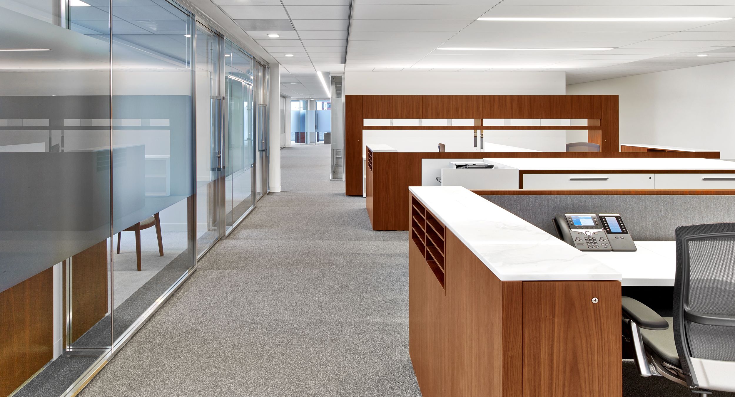 Beautifully-tailored private and open plan furniture unify the space in walnut, white, and chrome.