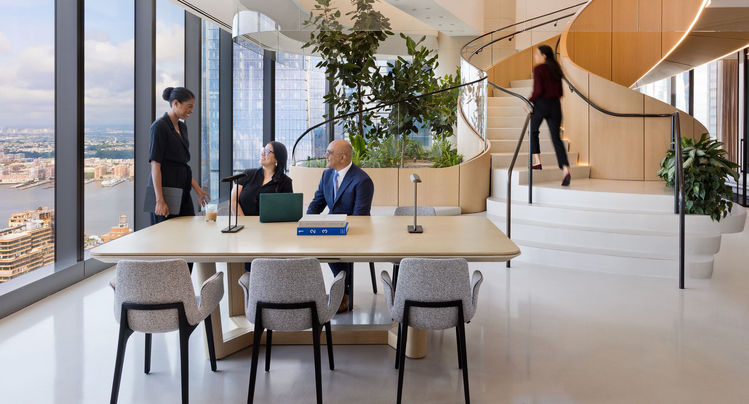 A White Oak Halo conference table with a wood base and Luxury Beige Halo Soft Edge is the perfect touchdown space in this bright and airy amenity area.
