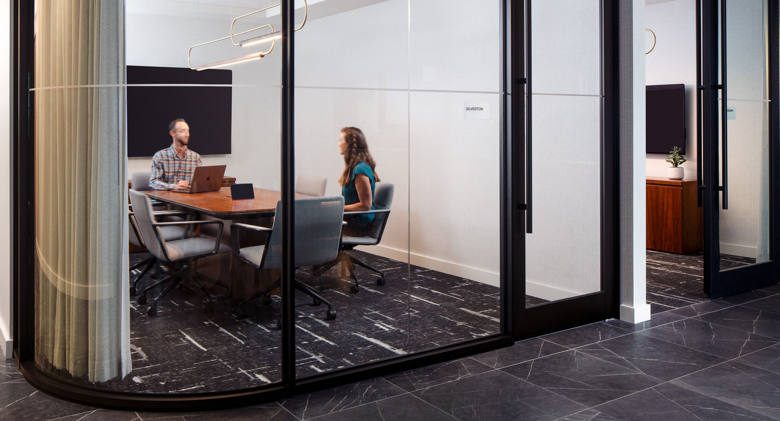 A small conference room with a 42d x 108w HALO continuous base conference table in Natural Flat Cut Walnut.