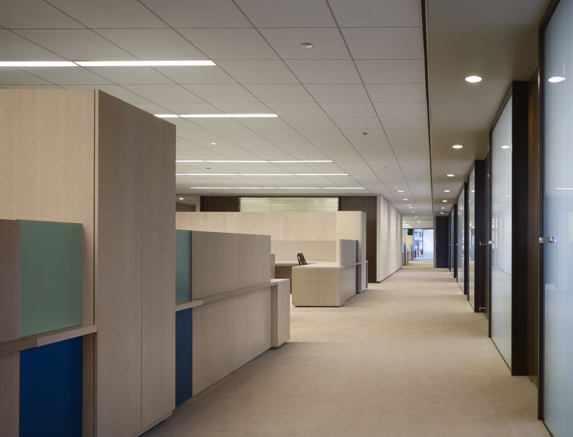 Stunning open office furniture achieves a layered elegance with the integration of ash veneer, tinted glass, and faux leather.