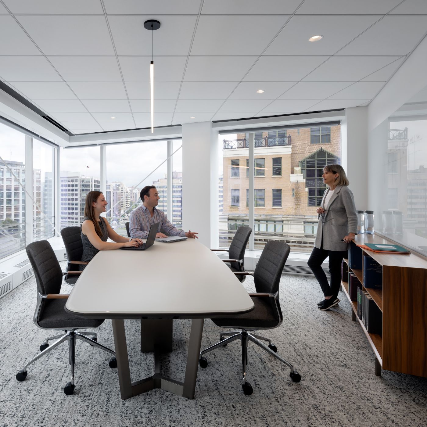 Soft-arc Halo table with Mink Halo soft edge, light bronze metal y-base, and a windham grey acid-etched glass surface. A custom Halo credenza in figured walnut completes this elegant meeting space.