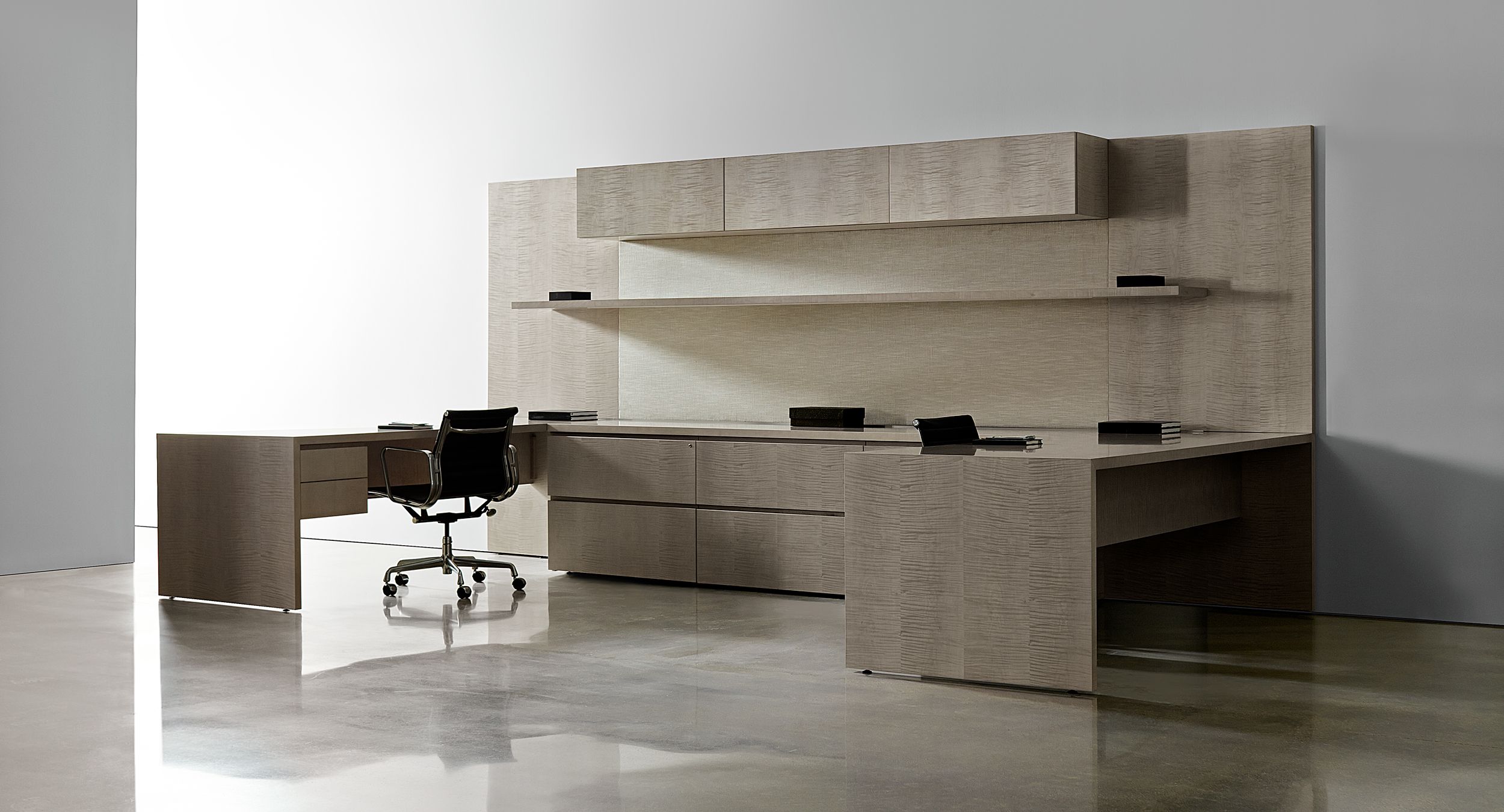 New Millennia features continuous open shelving, minimalist closed storage, and desking with raised storage and mitered joinery.