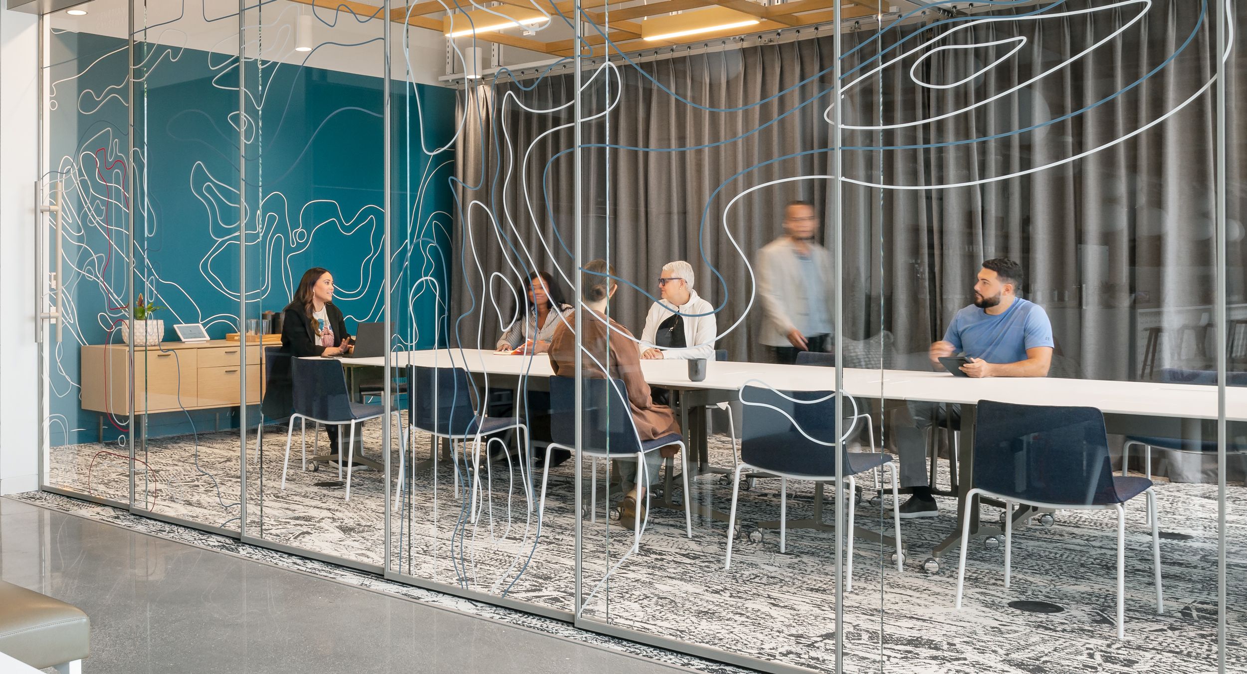 Skill mobile tables are light, modern, and refined. Shown here with FENIX NTM Bianco Kos surfaces and light bronze powder coat bases. A Halo credenza with matching anodized base and pulls completes the space.