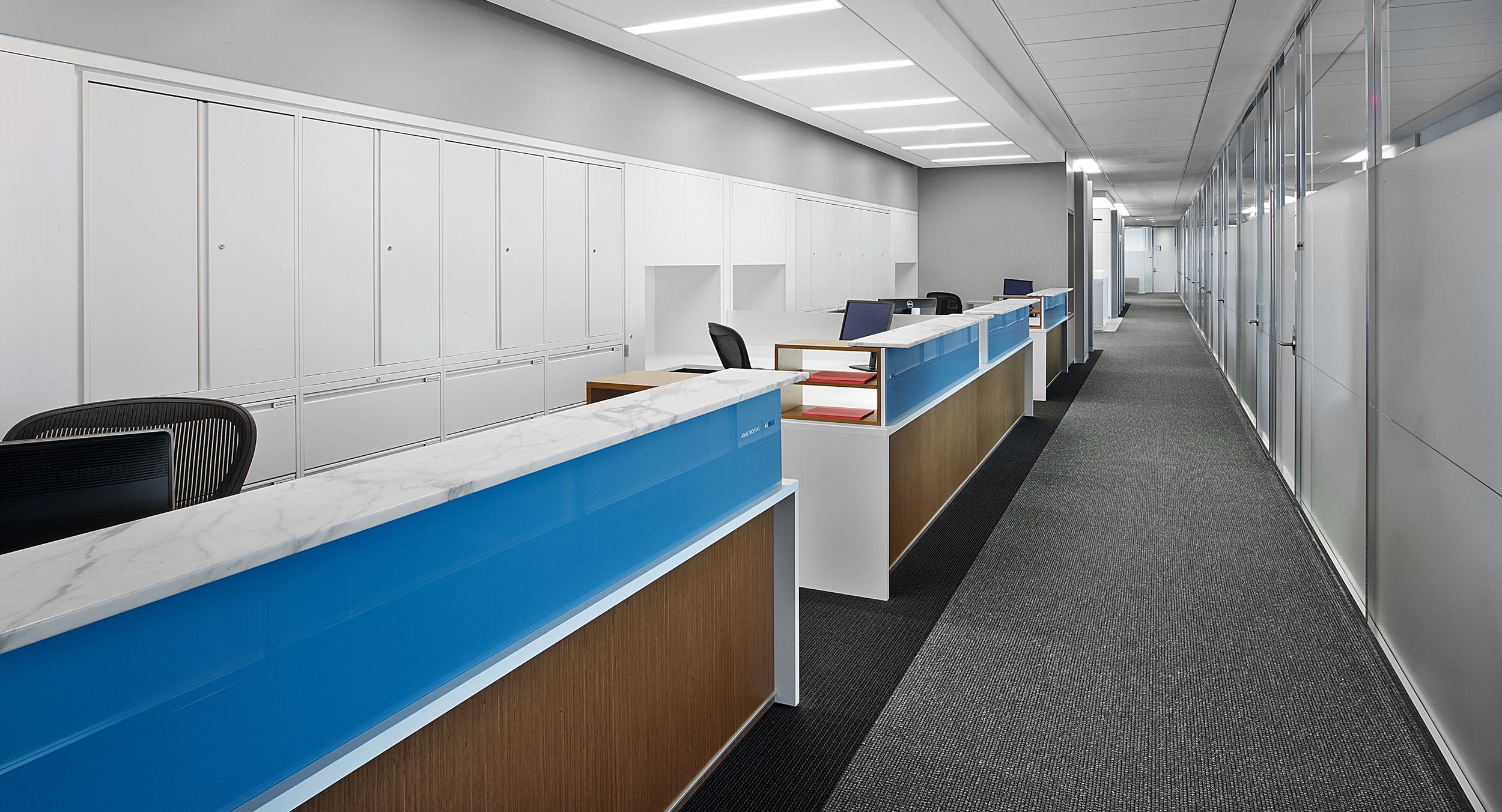 Administrative stations featured stone transaction counters, blue tinted glass, frosted acrylic privacy screen, white laminate and wood surround panels with satin aluminum base accent trim.