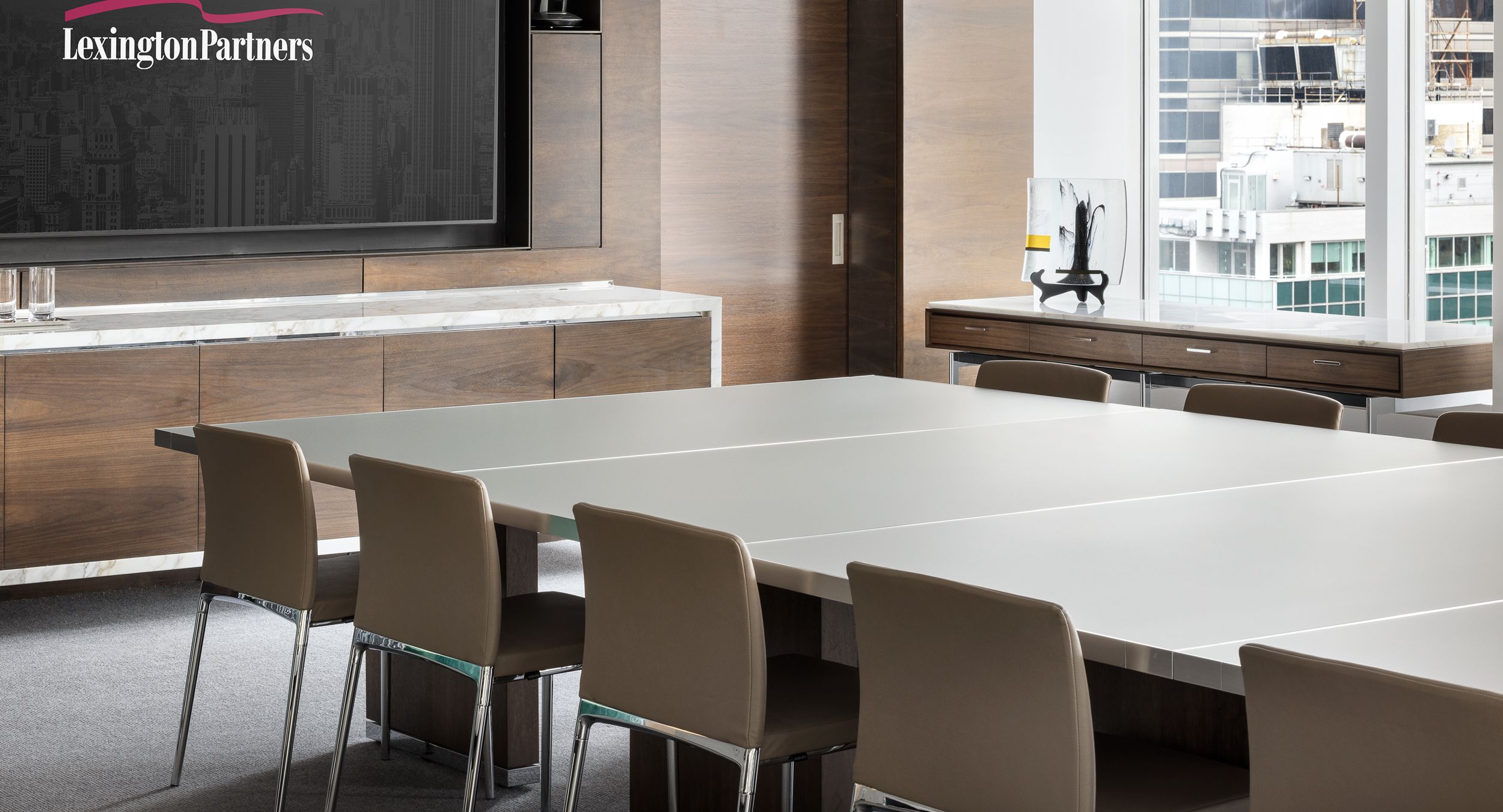 Luxurious finishes like the back-painted etched glass MOTUS surfaces and Calacatta stone topped HALO credenza are centerpieces of this sophisticated space.