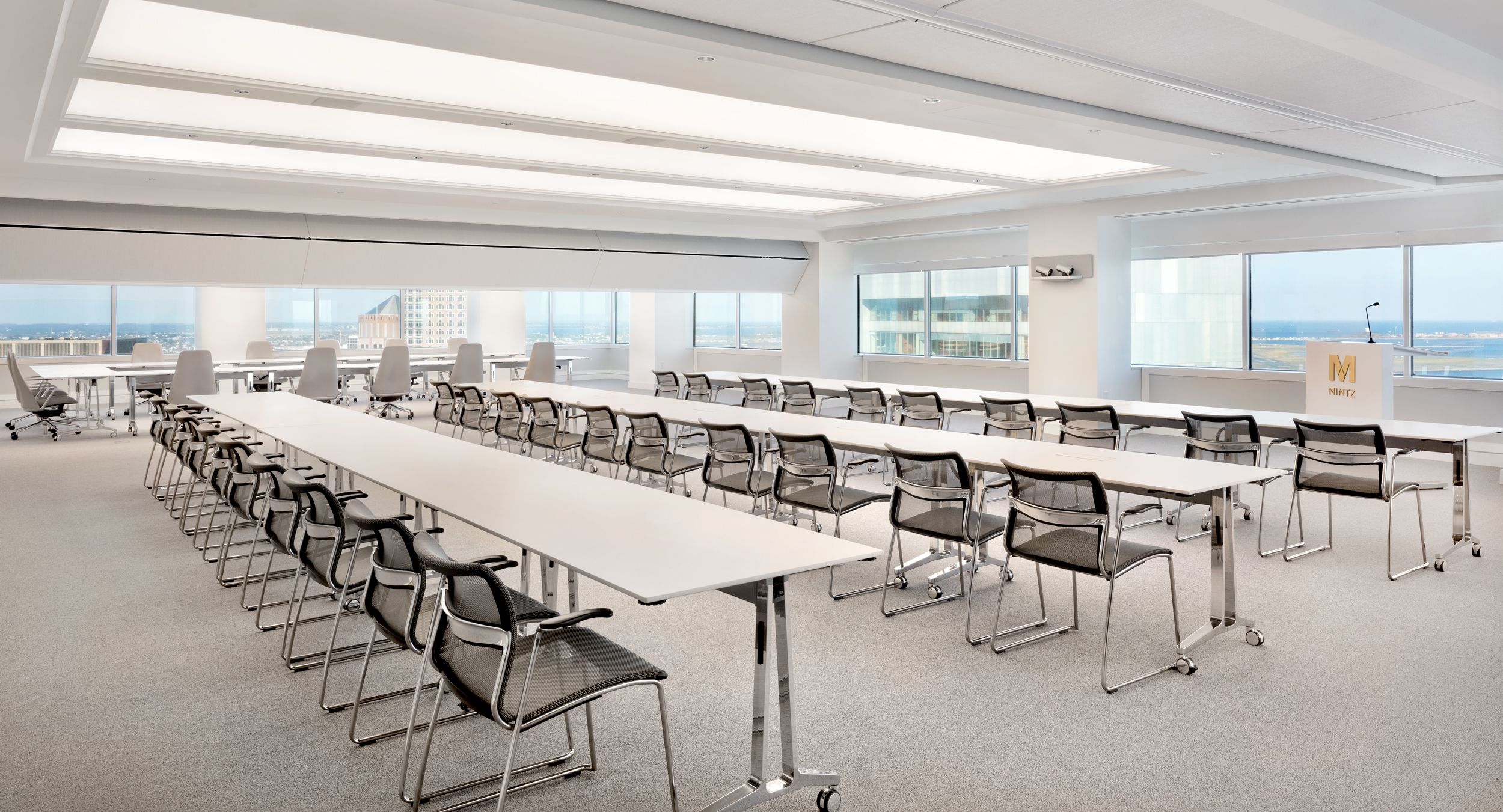 SKILL reconfigurable tables with polished aluminum bases and white Fenix surfaces. A MOTUS mobile lectern in designer white completes this flexible space.